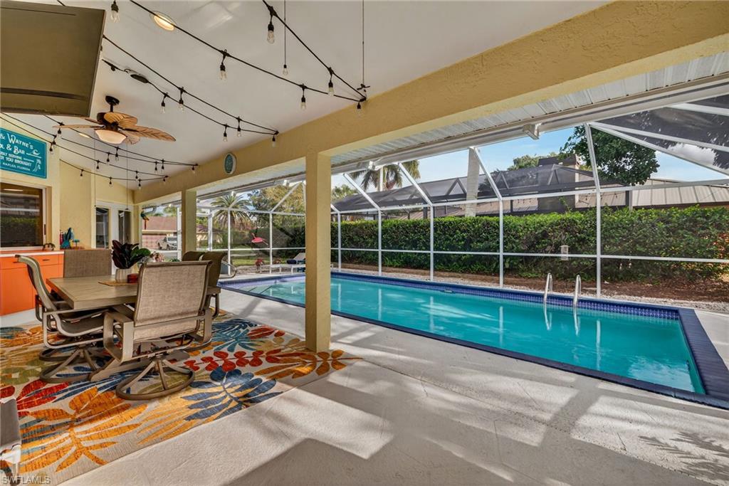 View of swimming pool with patio surround, outdoor dining space, a sunroom, and a lanai