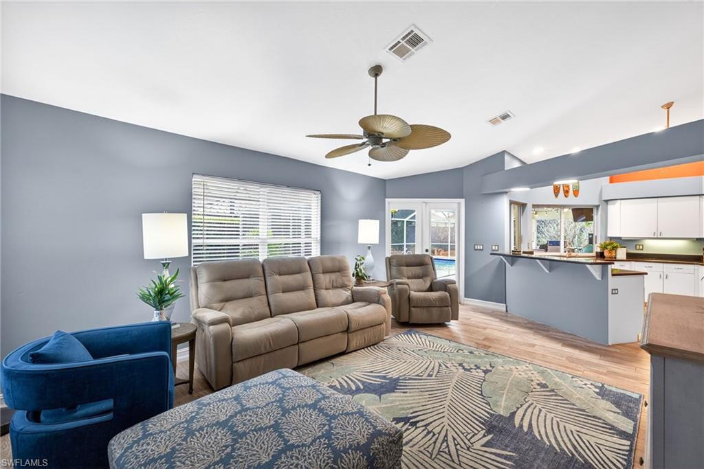 Living area with light wood-type flooring, ceiling fan, french doors, and lofted ceiling