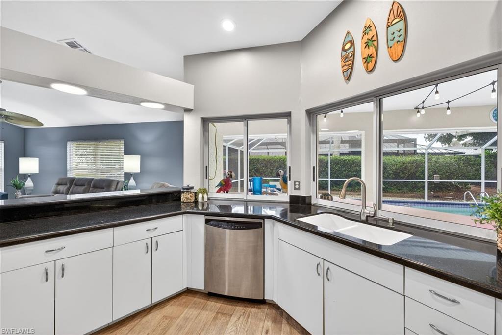 Kitchen featuring dishwasher, dark stone countertops, white cabinets, and open floor plan