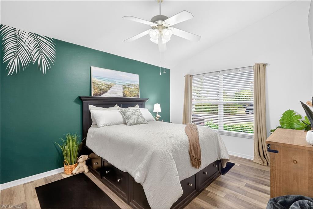 Bedroom featuring light wood-style flooring, vaulted ceiling, and a ceiling fan