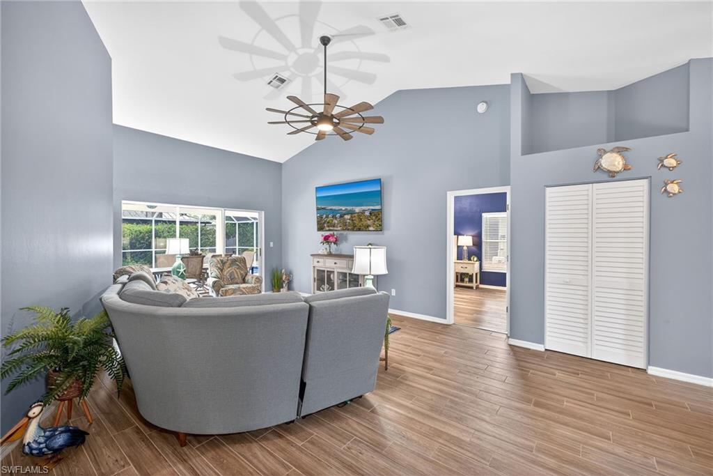 Living room featuring ceiling fan, wood tiled floors, and vaulted ceiling