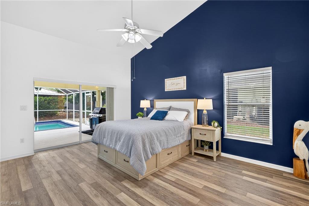 Bedroom featuring a sunroom, access to exterior, vaulted ceiling, light wood finished floors, and ceiling fan