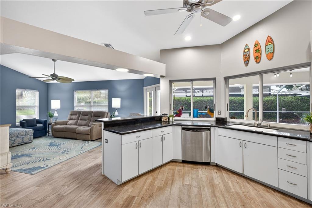 Kitchen with a ceiling fan, white cabinets, open floor plan, dishwasher, and light wood finished floors