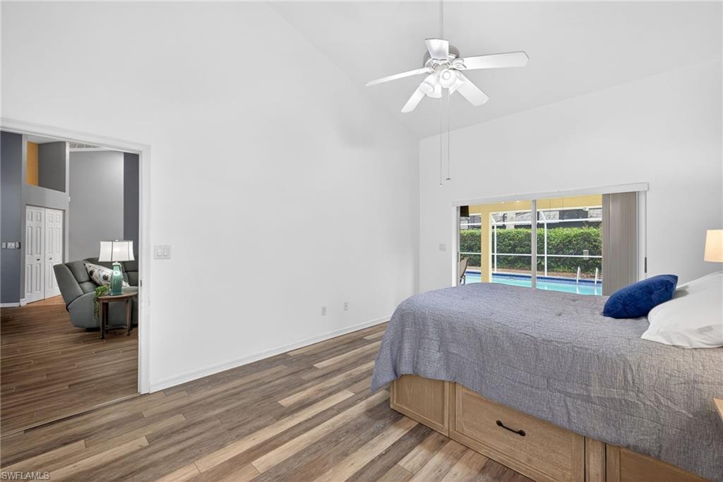 Bedroom with dark wood finished floors, access to exterior, lofted ceiling, and ceiling fan