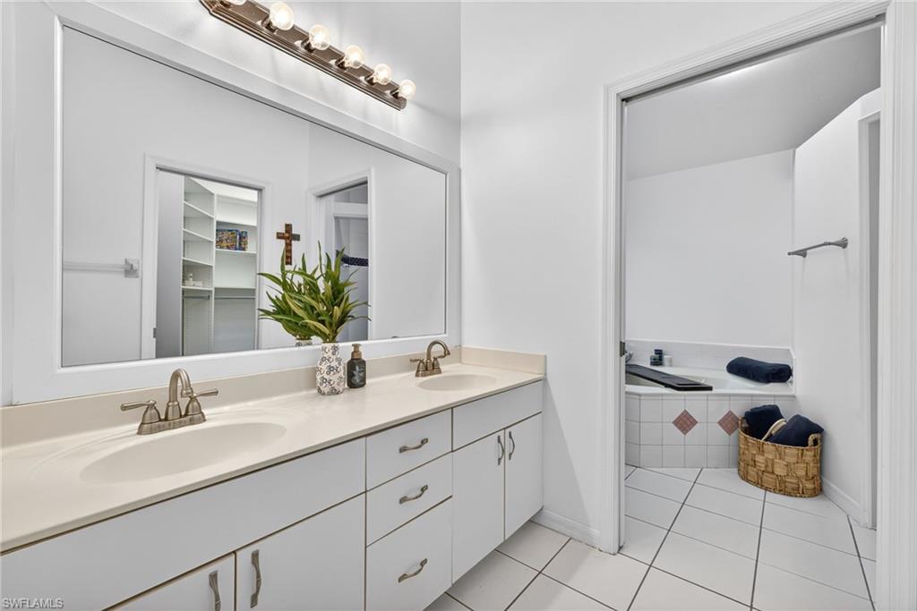 Bathroom featuring double vanity, a bath, light tile patterned flooring, and a walk in closet