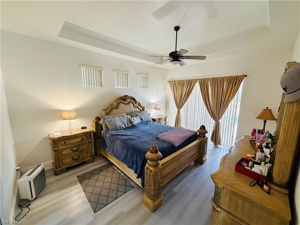 Bedroom featuring a raised ceiling, wood finished floors, and a ceiling fan
