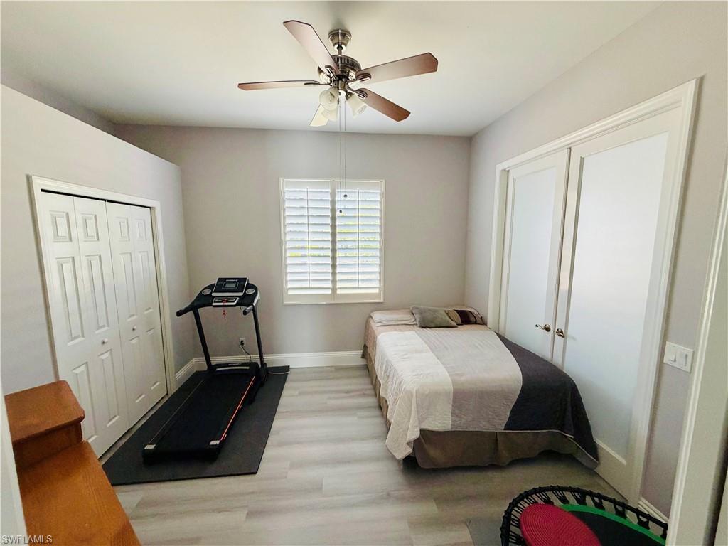Bedroom with light wood-type flooring, a ceiling fan, and multiple closets