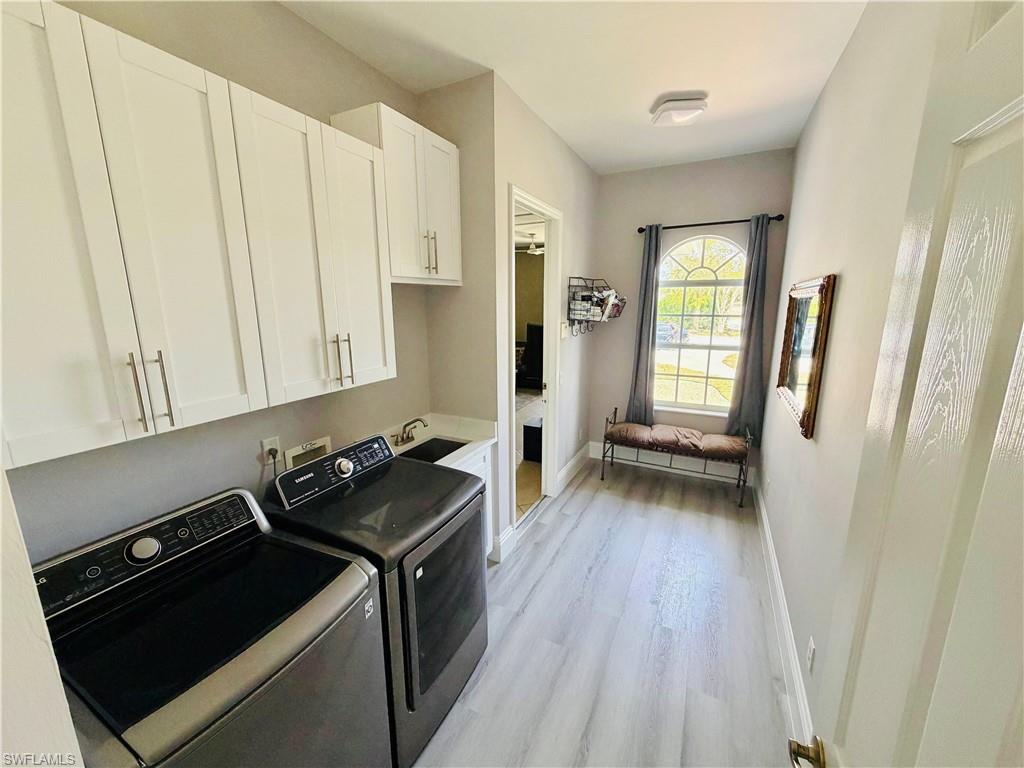 Laundry area featuring cabinet space, light wood-type flooring, and washing machine and clothes dryer