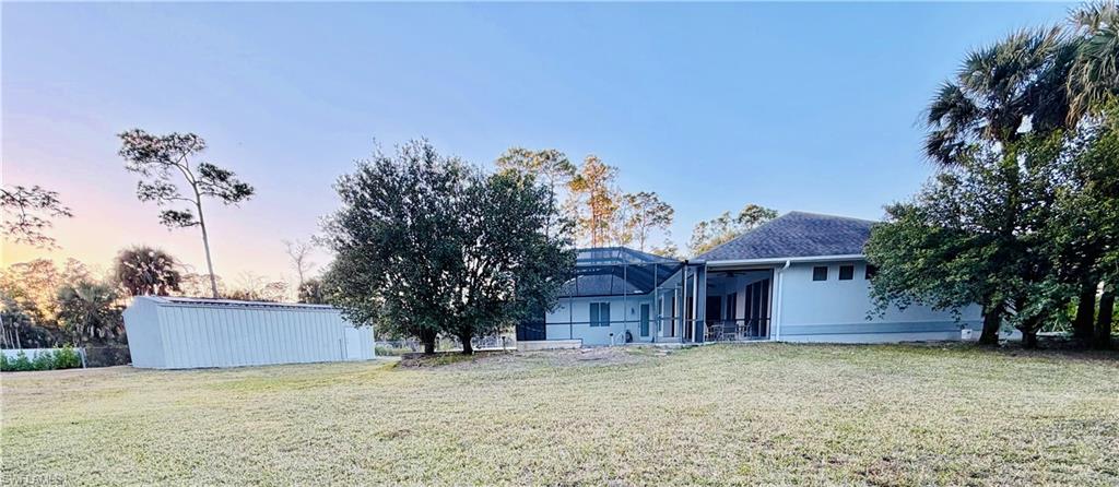 Back of property featuring a lanai, a lawn, and a sunroom