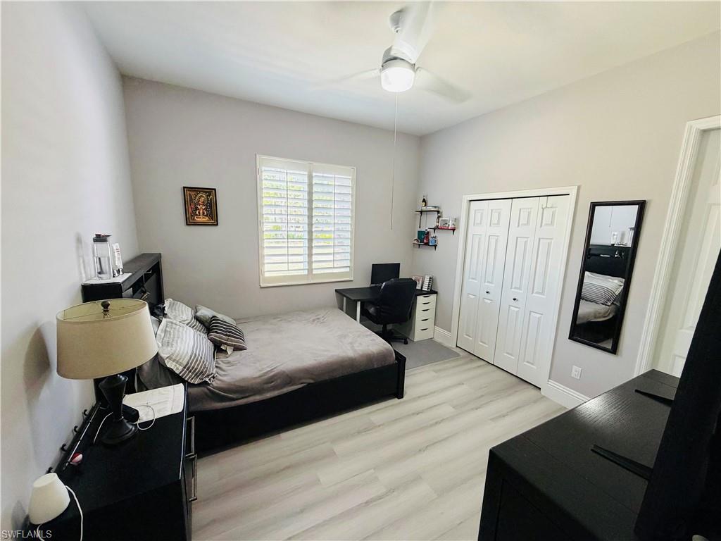 Bedroom featuring light wood finished floors, an office area, a closet, and a ceiling fan