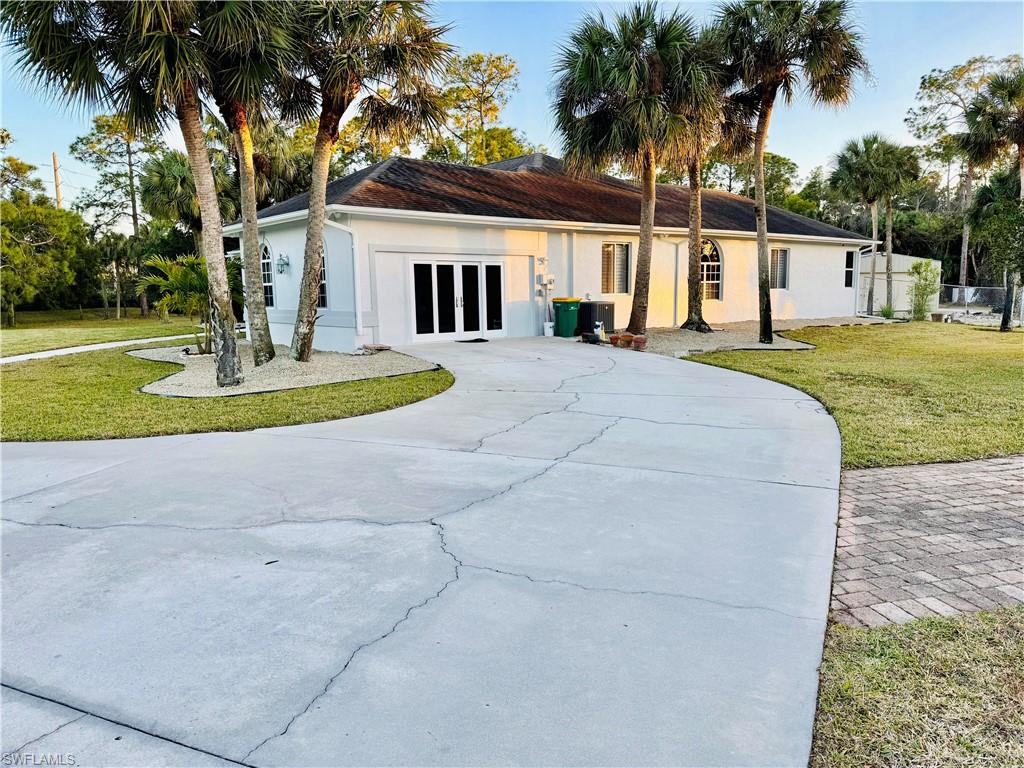 Single story home with a front yard, stucco siding, concrete driveway, and french doors