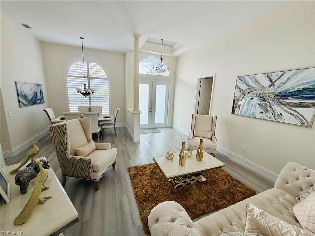 Living area with light wood-type flooring, suspended lighting, and french doors