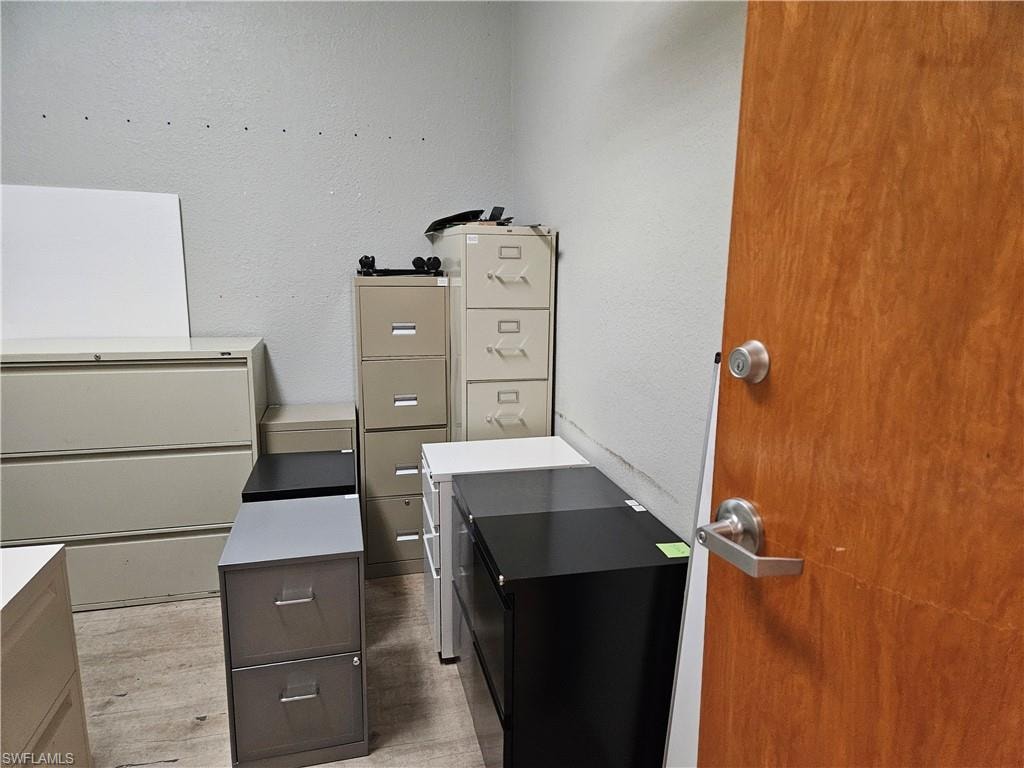 Unfurnished office with light wood-type flooring and a textured wall