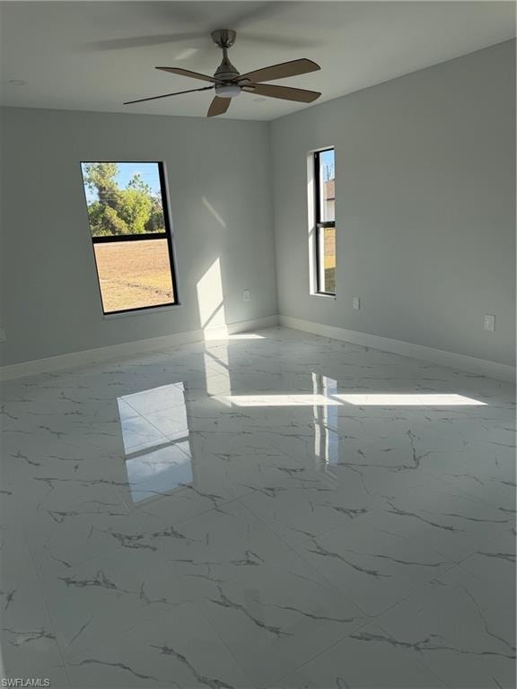 Unfurnished room with ceiling fan and light marble finish flooring