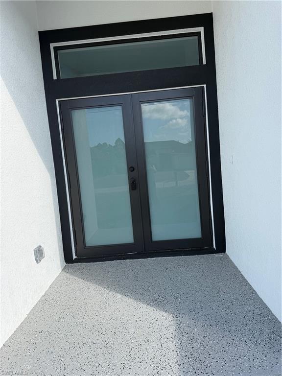 View of exterior entry featuring french doors and stucco siding