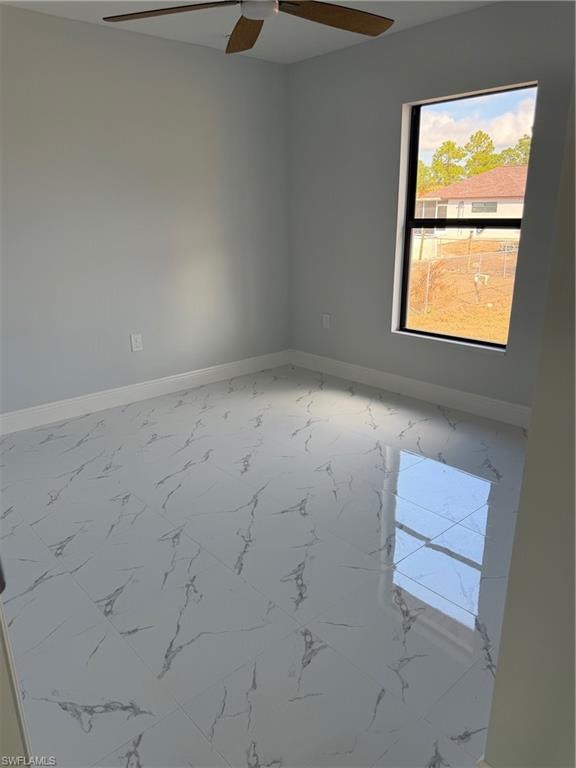 Spare room featuring light marble finish flooring and ceiling fan