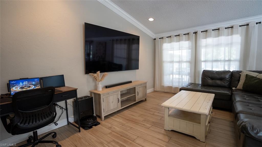 Living area featuring crown molding, a textured ceiling, light wood finished floors, and an office area