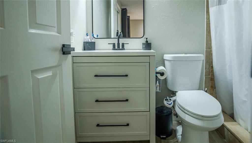 Bathroom featuring a textured wall, vanity, and a shower with shower curtain