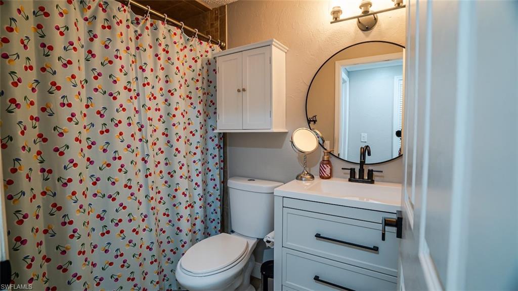 Full bathroom featuring vanity, a textured wall, and a shower with curtain