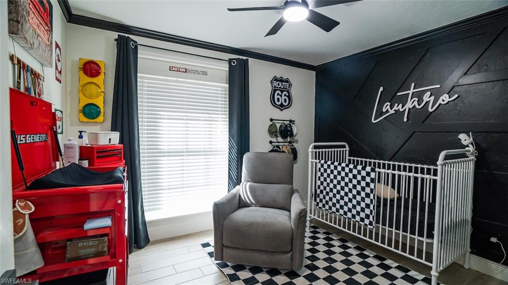 Bedroom featuring ornamental molding, a ceiling fan, a crib, and light wood-type flooring