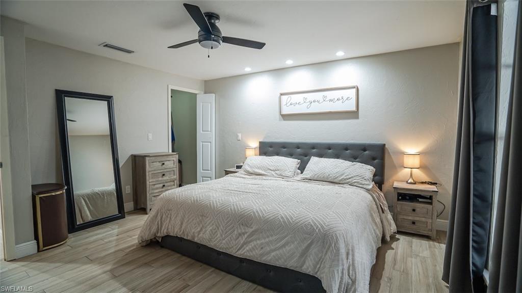 Bedroom with light wood-type flooring, ceiling fan, recessed lighting, and a textured wall
