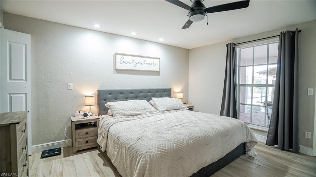 Bedroom featuring light wood-style flooring, a textured wall, a ceiling fan, and recessed lighting