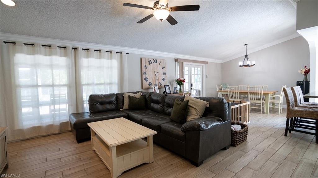 Living area featuring a ceiling fan, crown molding, wood finish floors, and hanging lights