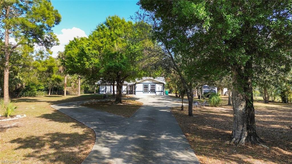 View of front of house featuring driveway and view of wooded area