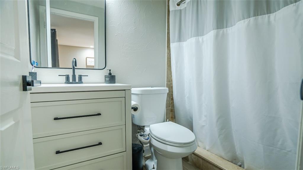 Bathroom with a textured wall, vanity, and a stall shower