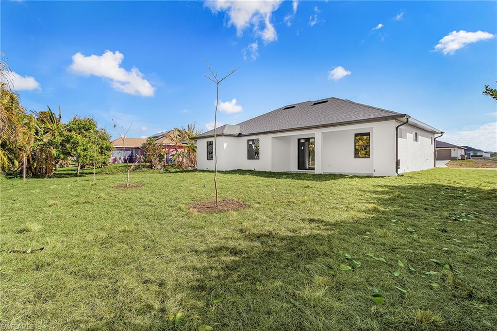 Back of property with stucco siding and a yard