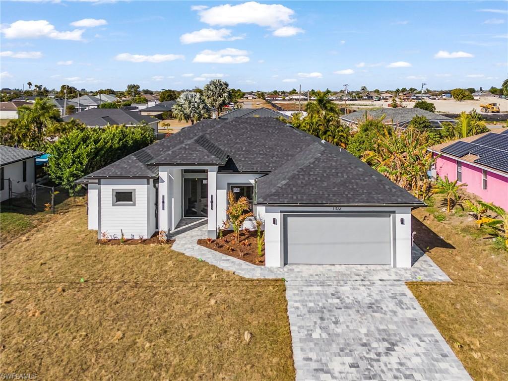 Ranch-style home with decorative driveway, a garage, a front lawn, a shingled roof, and a residential view