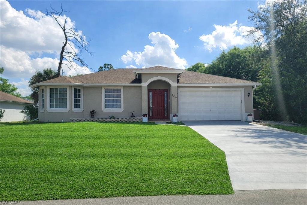 View of front of property featuring stucco siding, a front yard, concrete driveway, and a garage