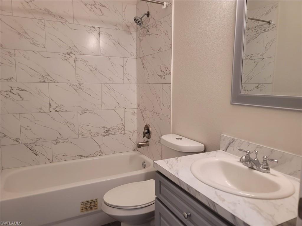 Bathroom featuring bathing tub / shower combination, vanity, and a textured wall