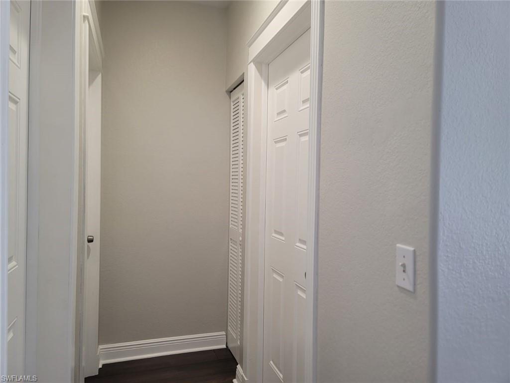 Corridor with dark wood-style floors and a textured wall