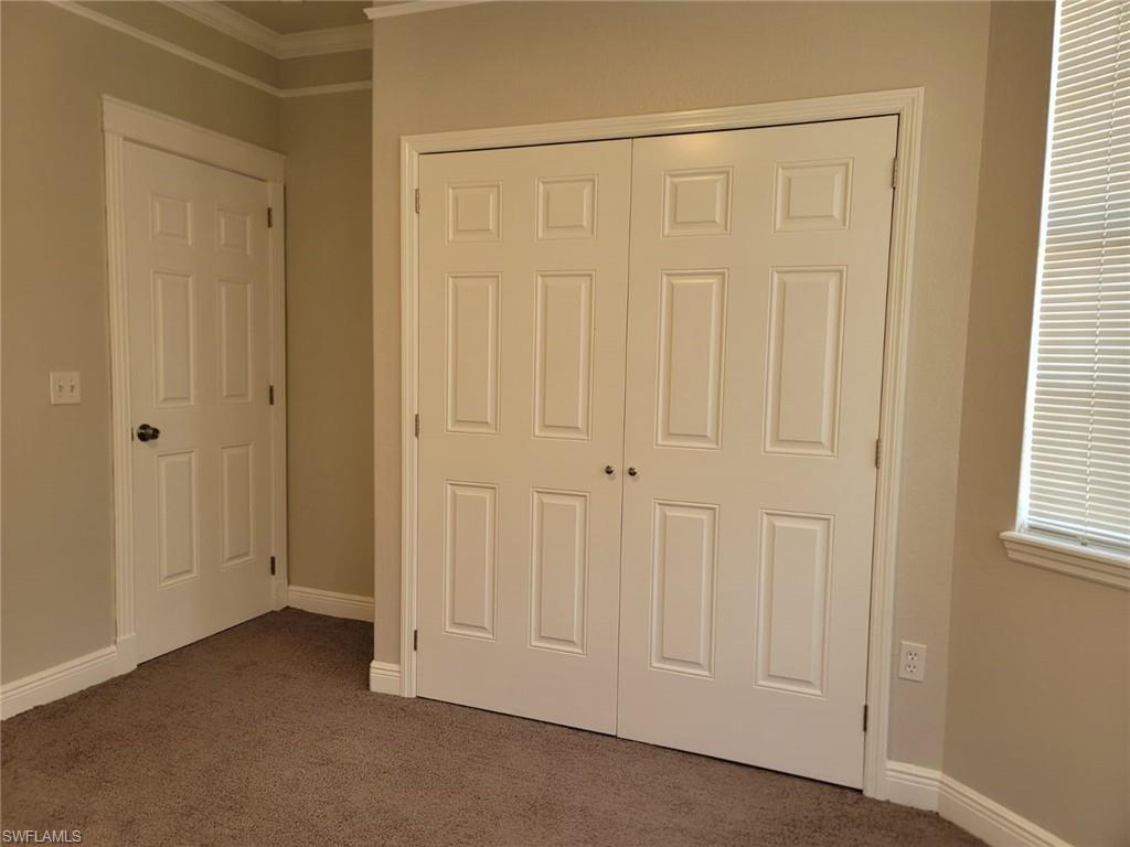 Unfurnished bedroom featuring dark carpet, a closet, and ornamental molding
