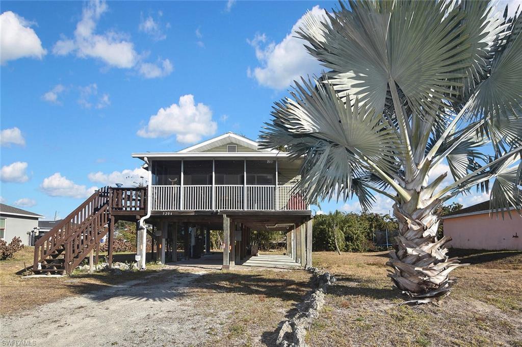 Back of house with a sunroom, a deck, a carport, and driveway
