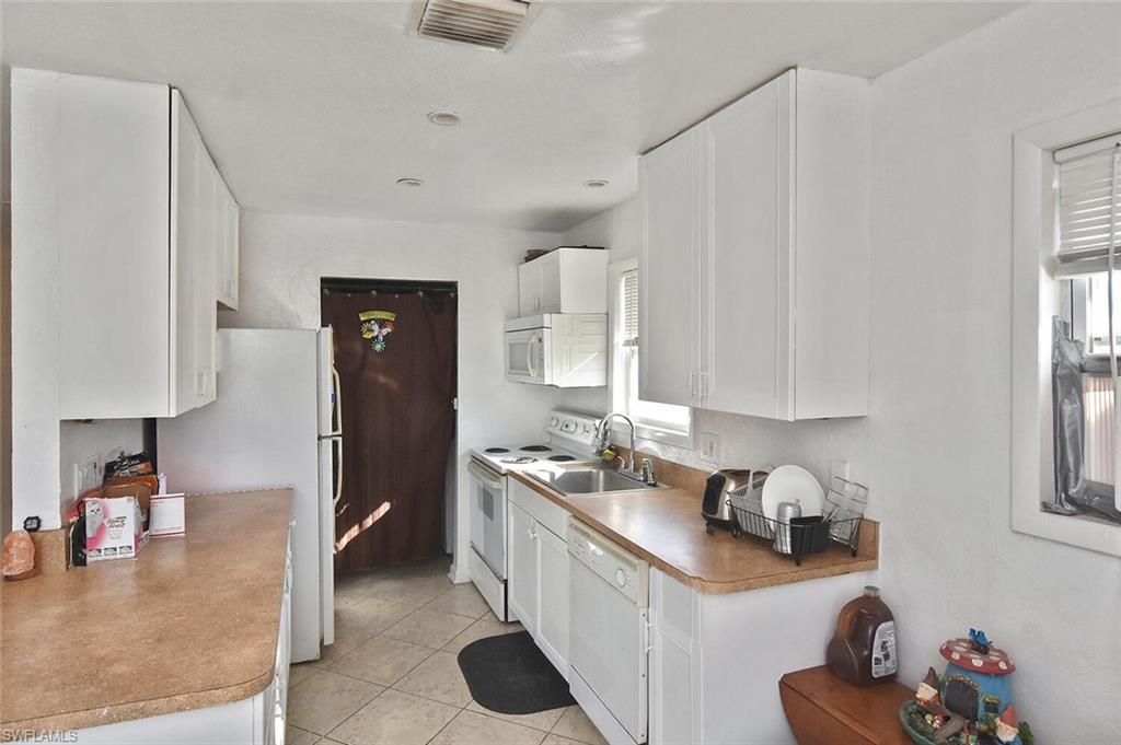 Kitchen featuring white cabinets, white appliances, and light tile patterned floors