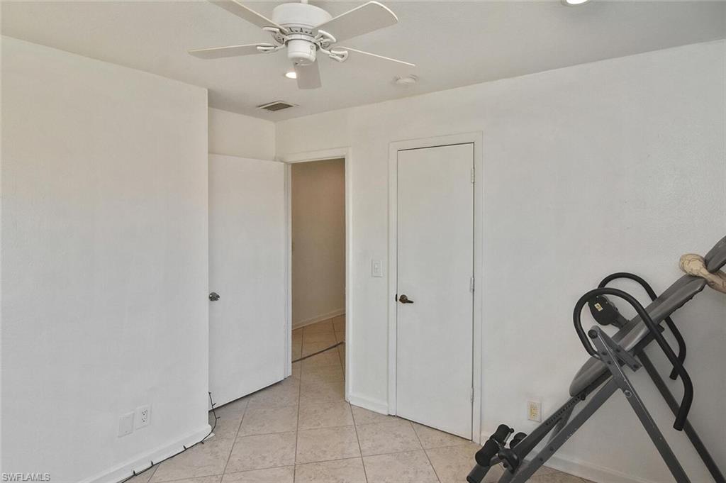 Workout area with a ceiling fan and light tile patterned floors