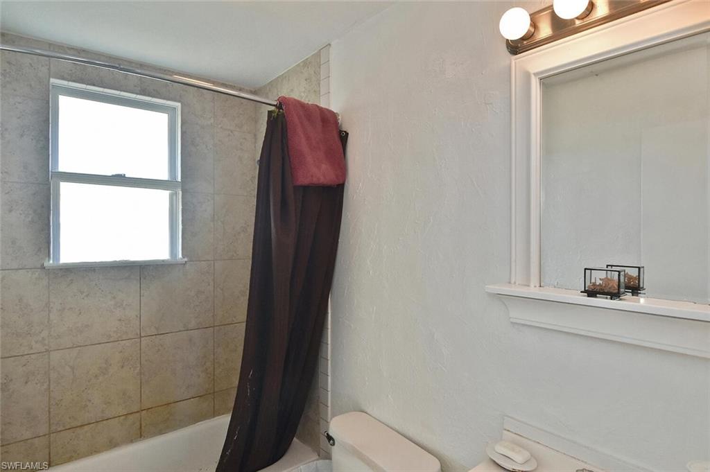 Bathroom featuring shower / tub combo with curtain and a textured wall