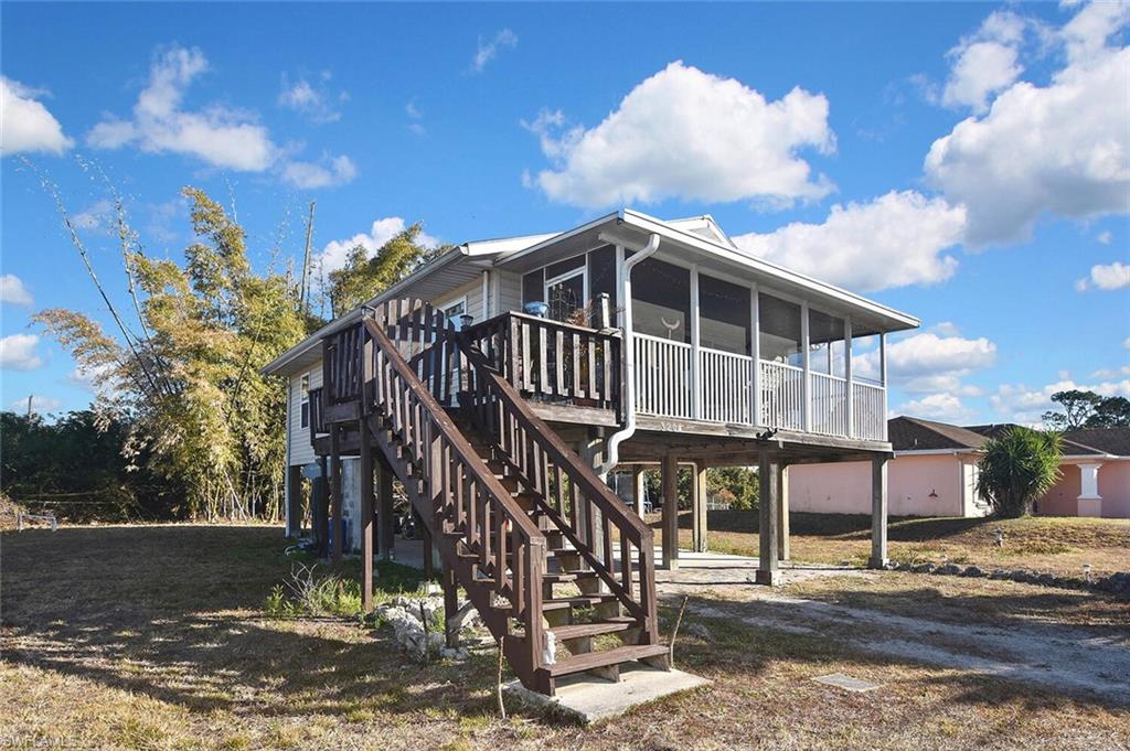 Back of house featuring a wooden deck, a sunroom, and a yard