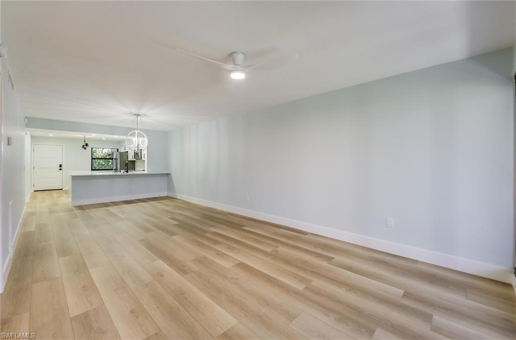 Unfurnished living room with a chandelier, ceiling fan, and light wood-style floors