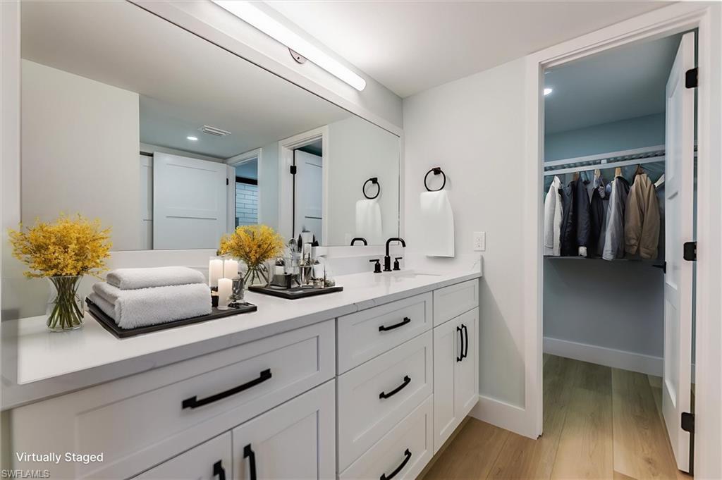 Bathroom with a walk in closet, double vanity, light wood-style flooring, and recessed lighting
