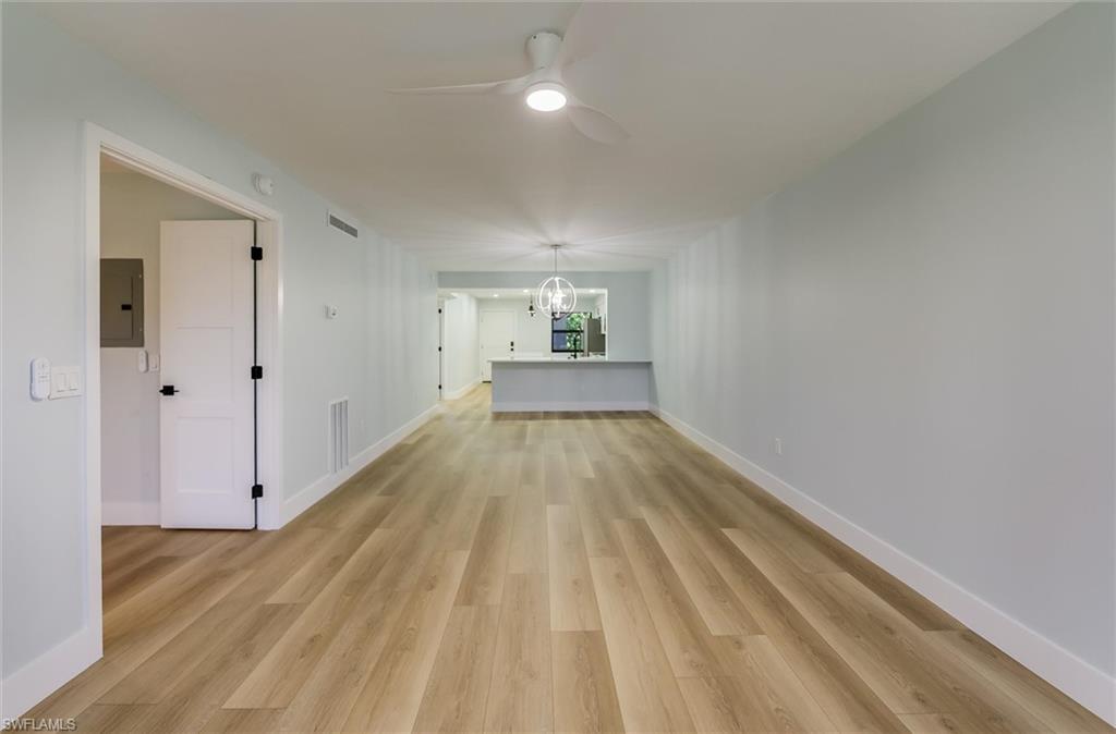 Unfurnished room with ceiling fan, light wood-style flooring, a chandelier, and electric panel