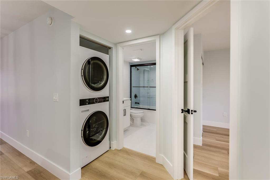 Laundry area with stacked washer / dryer, light wood-style floors, and recessed lighting