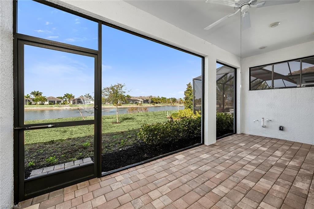 Unfurnished sunroom with ceiling fan, a water view, and a residential view