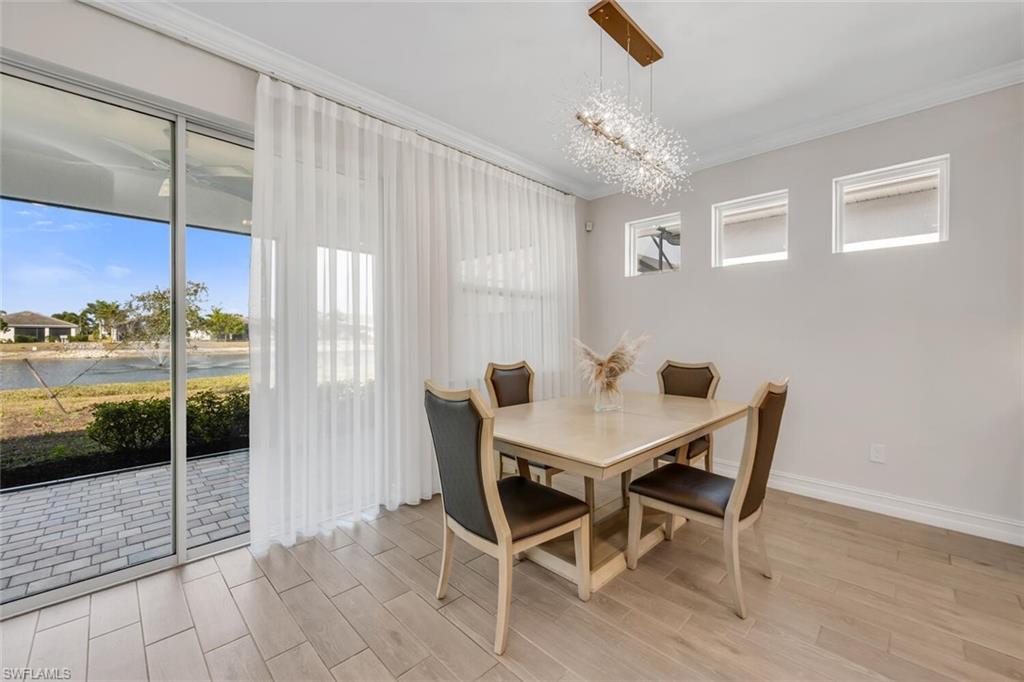 Dining space featuring crown molding, wood finish floors, hanging lights, and a water view