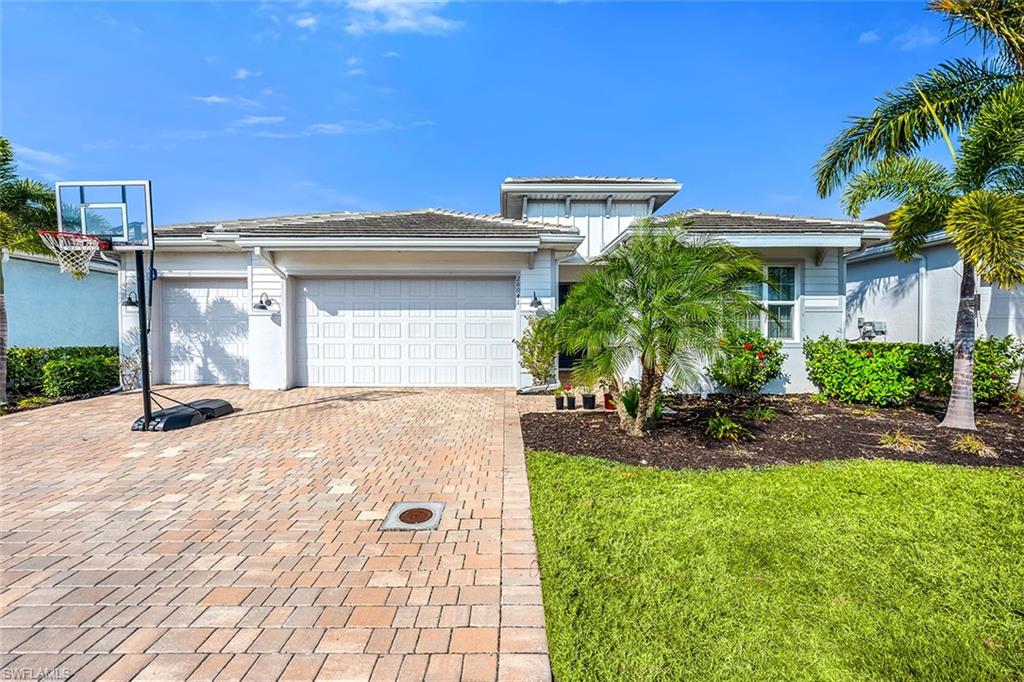 Prairie-style house with an attached garage, decorative driveway, and a front yard