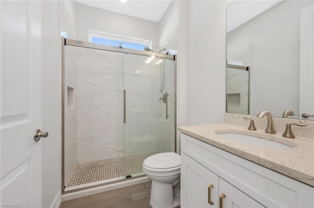 Bathroom with vanity and a marble finish shower