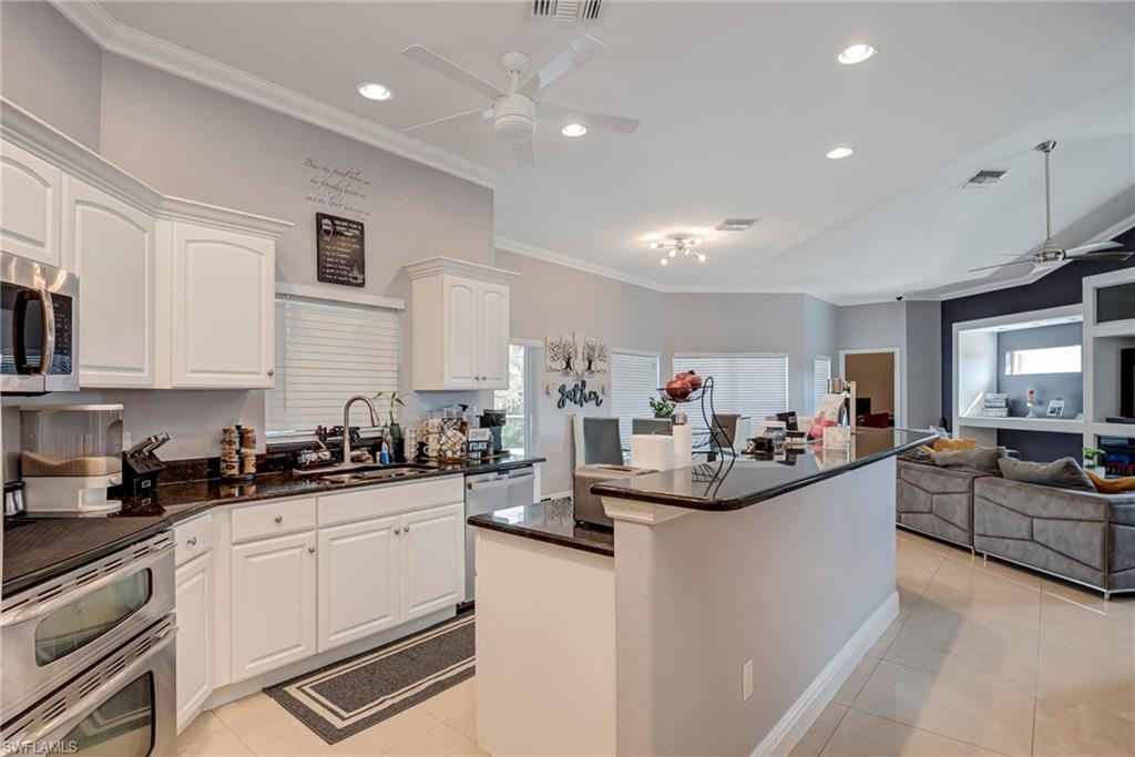 Kitchen with a ceiling fan, crown molding, dark stone countertops, recessed lighting, and light tile patterned floors