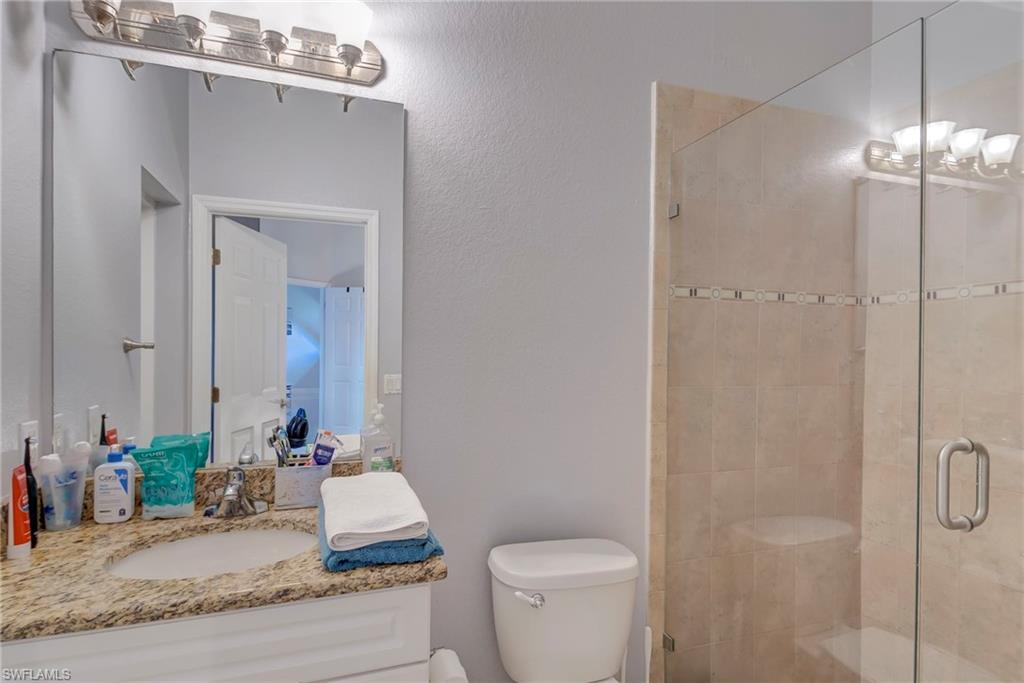 Full bath featuring a shower stall, vanity, and a textured wall